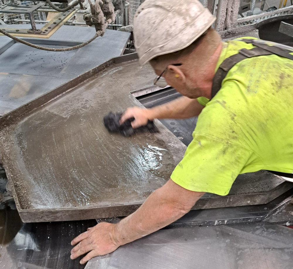 VGM Breed Nieuws - Man met witte helm en geel shirt is bezig met de hand olie aan te brengen op een plaat.